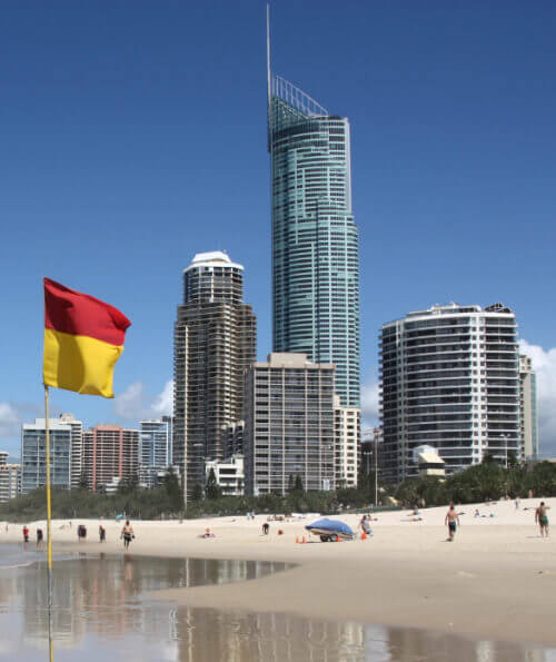 Q1 tower and Surfers Paradise skyline from the beach with surf lifesaving flag