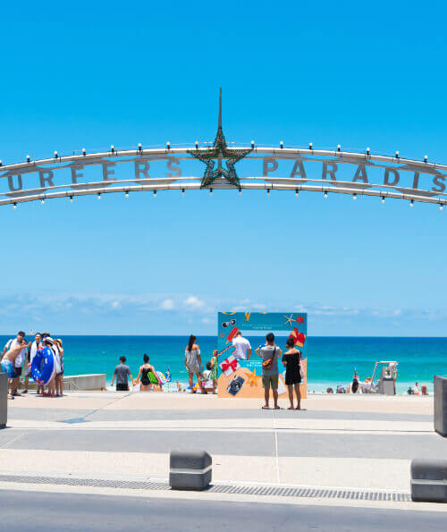 Tourists under the Surfers Paradise arch sign on a sunny Gold Coast day